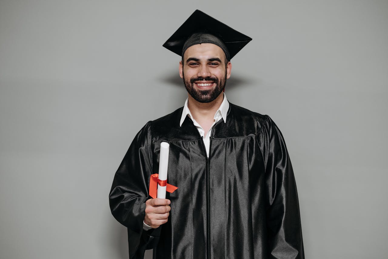 Happy bearded man in graduation attire, celebrating academic success.